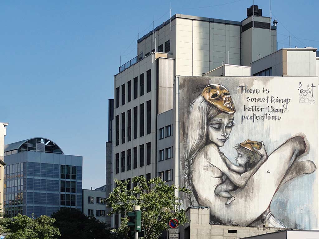 Mutter hält Baby in den Armen, flankiert vom Spruch There is something better than perfection