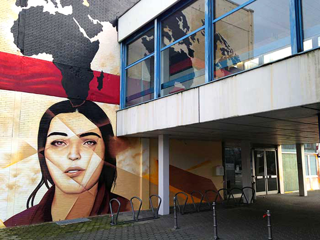 Gebäude-Mural mit roter Geschenkschleife und Antlitze von Adorno und Horkheimer