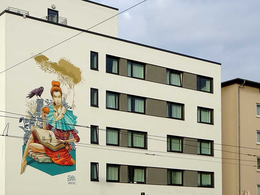 Hausfassadegestaltung zeigt eine Frau mit Buch und Apfel