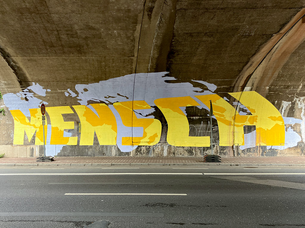 Gegenüberliegende Schriftzüge MENSCH und WÜRDE in Unterführung